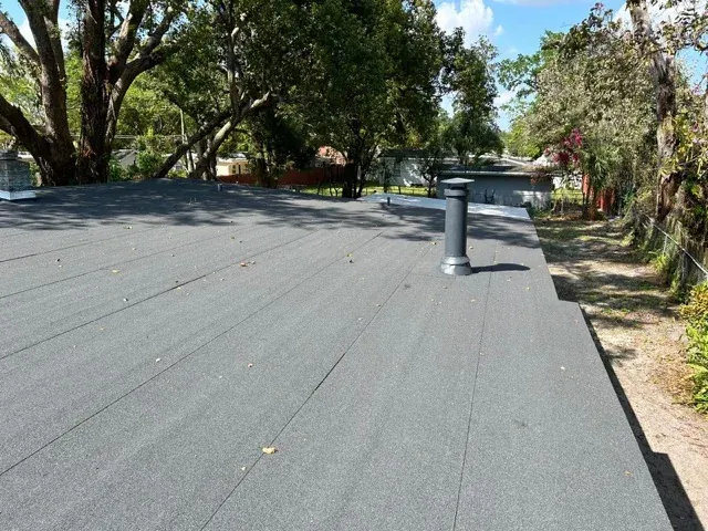 Finished low-slope roof with a granulated modified bitumen cap sheet, a sealed vent stack collar and a parapet edge
