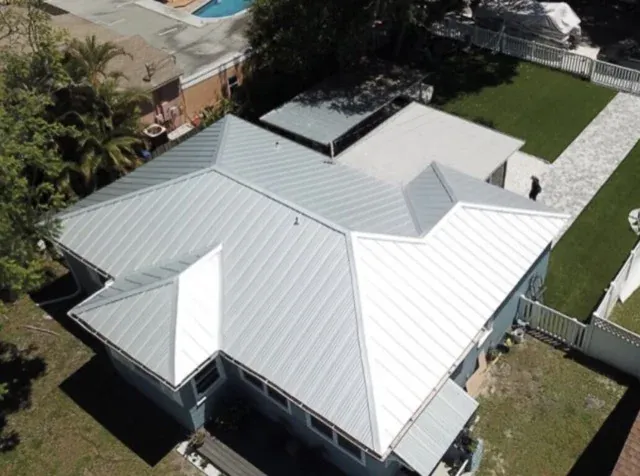 Completed standing seam metal roof photographed from above, showing hips, valleys and a low-slope porch section