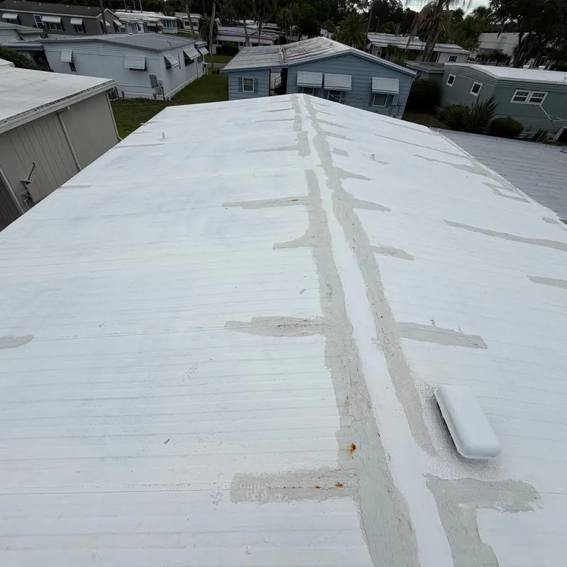White metal mobile home roof covered in old sealant patches along the seams