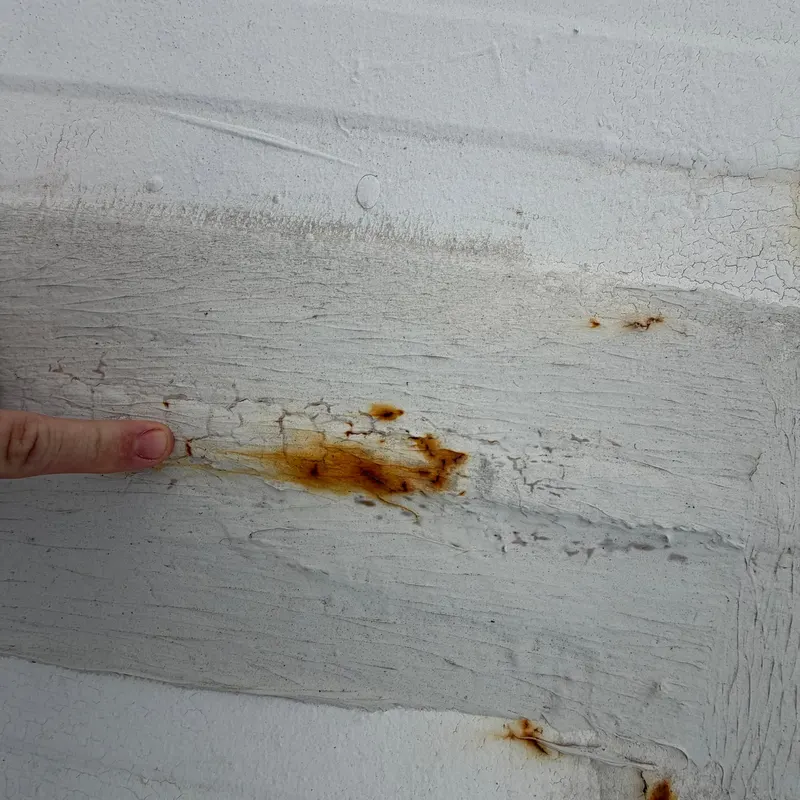 Rust bleeding through the old coating at a metal roof seam