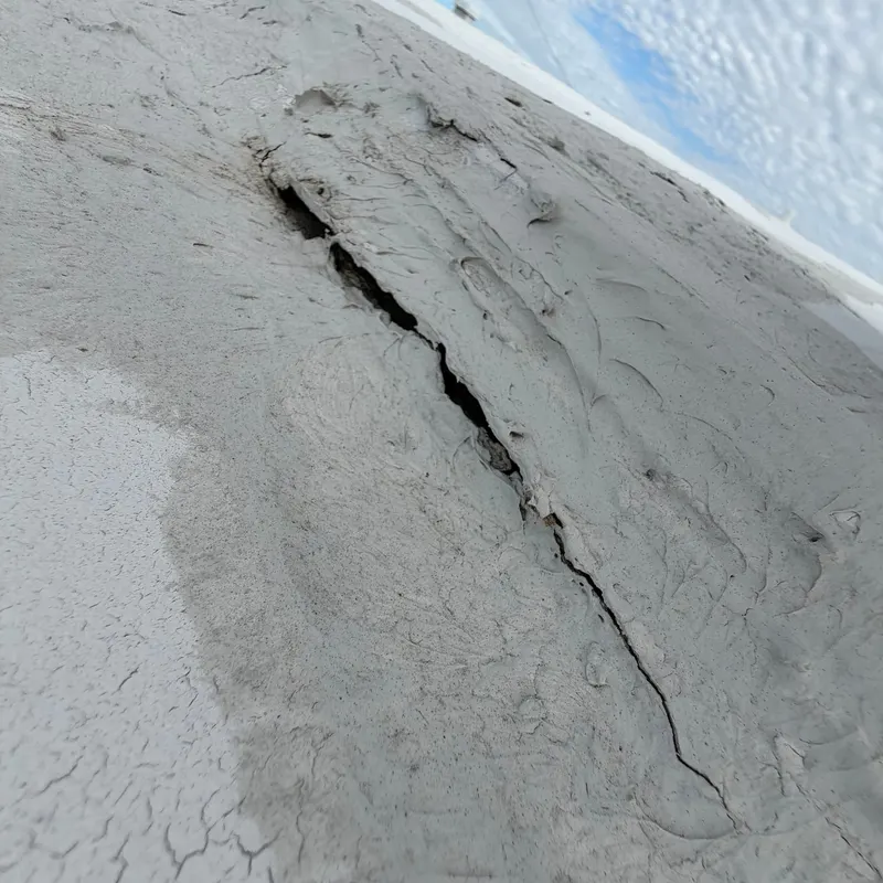 Old roof coating cracked and split open along the roof edge